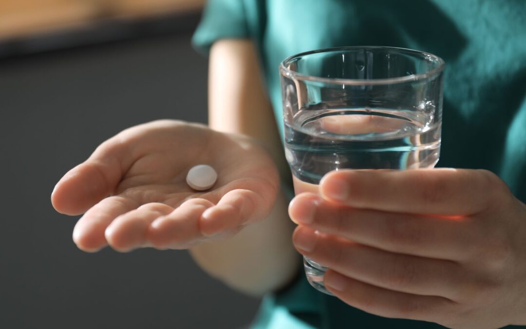 woman in green shirt taking abortion pill and water